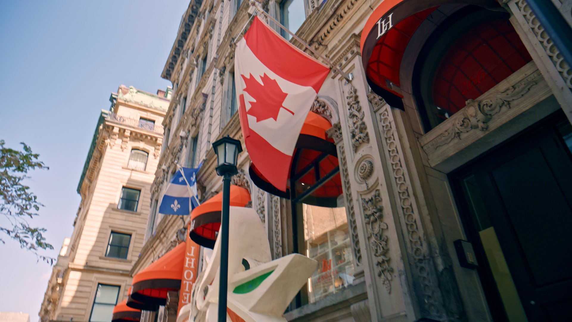 Canadian and Québec flags hanging outside a building in Old Montreal, still from R3D NE footage