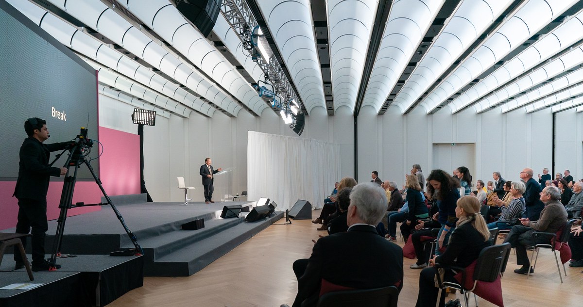 Filming a conference talk from the audience with a tripod-mounted camera